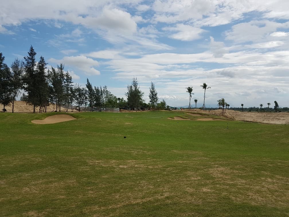 A bunkered green at Danang Golf Club fringed by casuarina pines and sandy dunes, Vietnam.