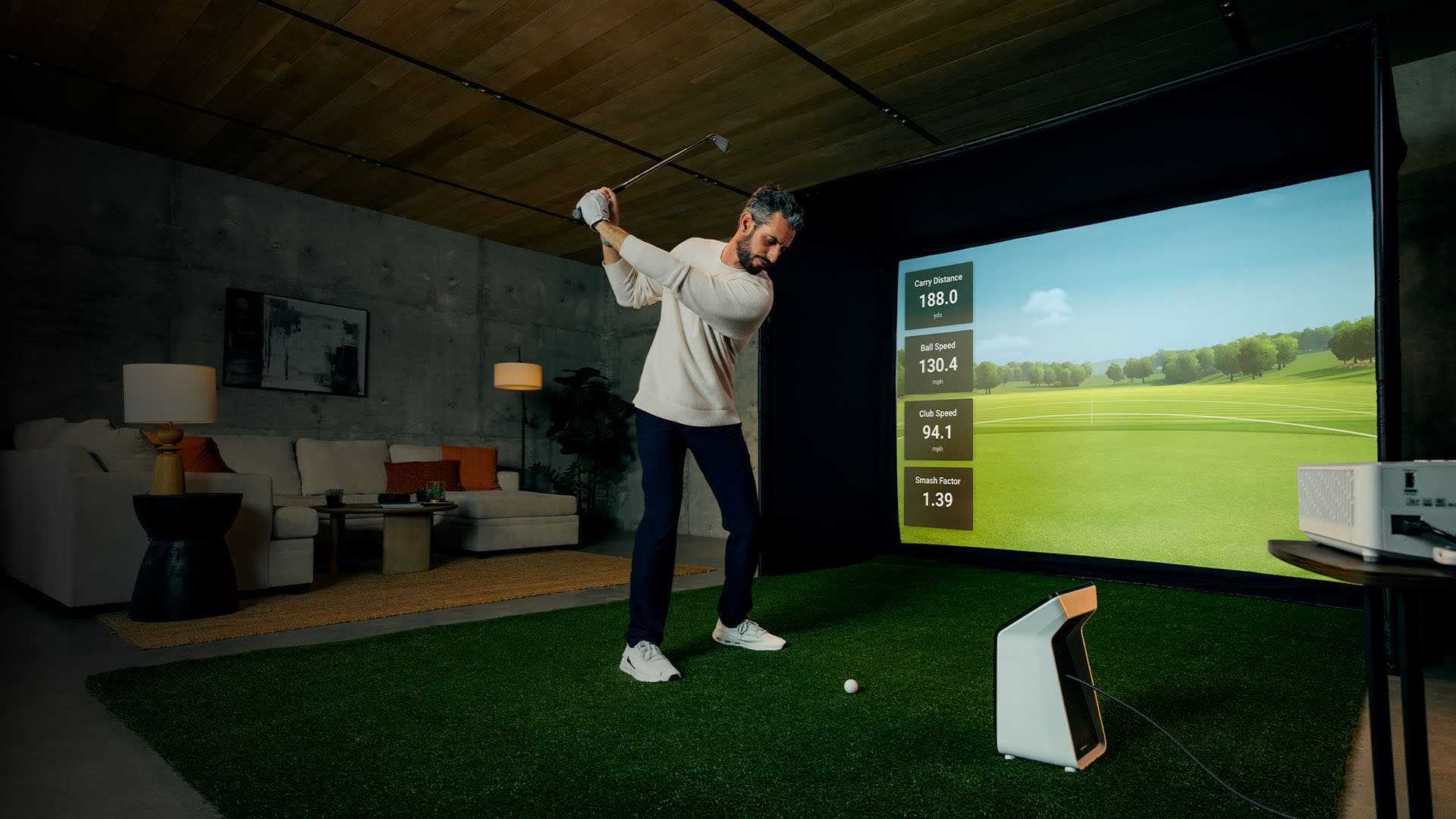 A stylish home golf simulator room with a launch monitor, projector and impact screen showing live shot data