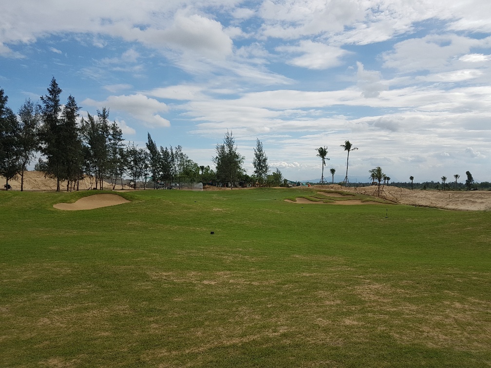 A bunkered green at Danang Golf Club fringed by casuarina pines and sandy dunes, Vietnam.