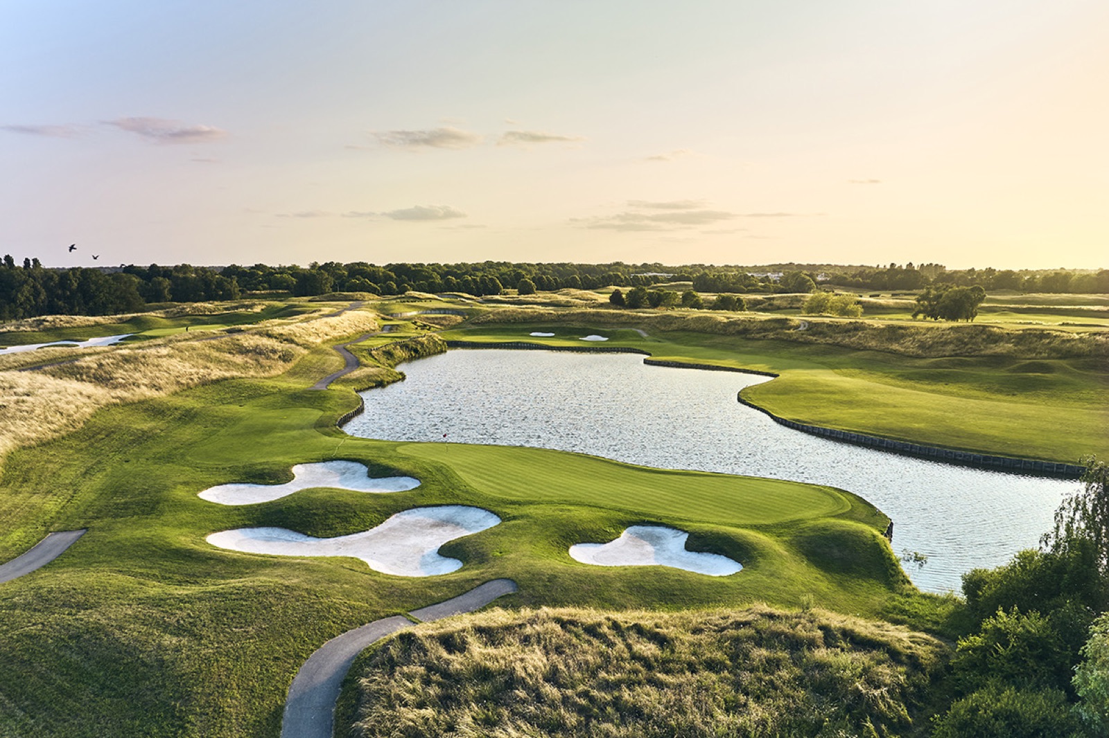 A golden-hour aerial of a bunkered, water-lined green on L'Albatros at Le Golf National, host of the 2018 Ryder Cup.