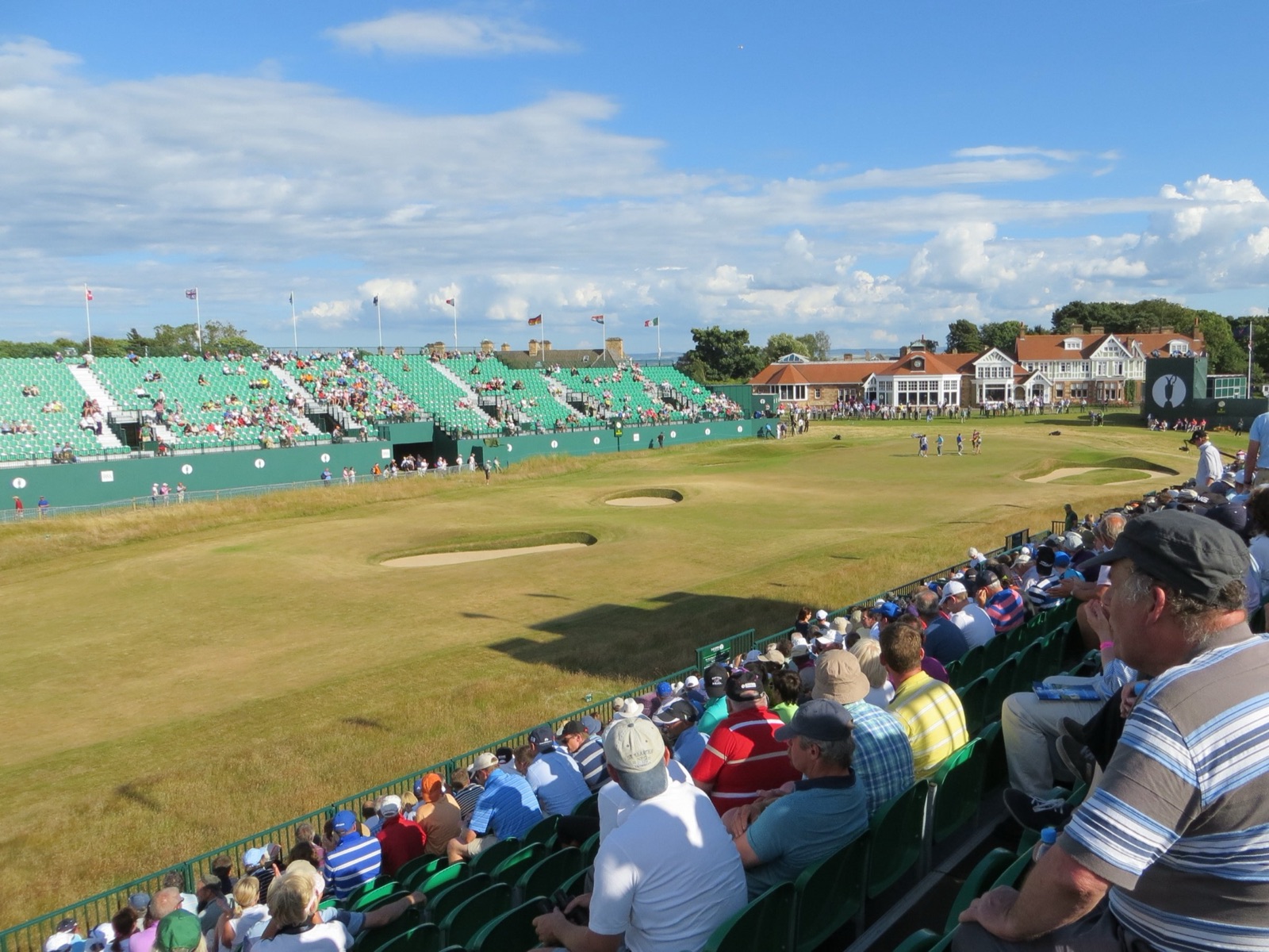 The 18th green and the clubhouse at Muirfield during the 2013 Open Championship, grandstands packed around the finish.